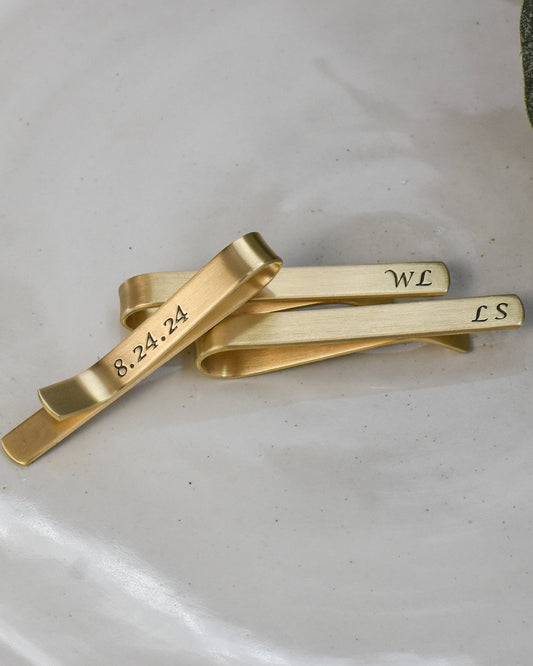 Personalized gold brass tie clip with hidden date on back in calligraphy font.