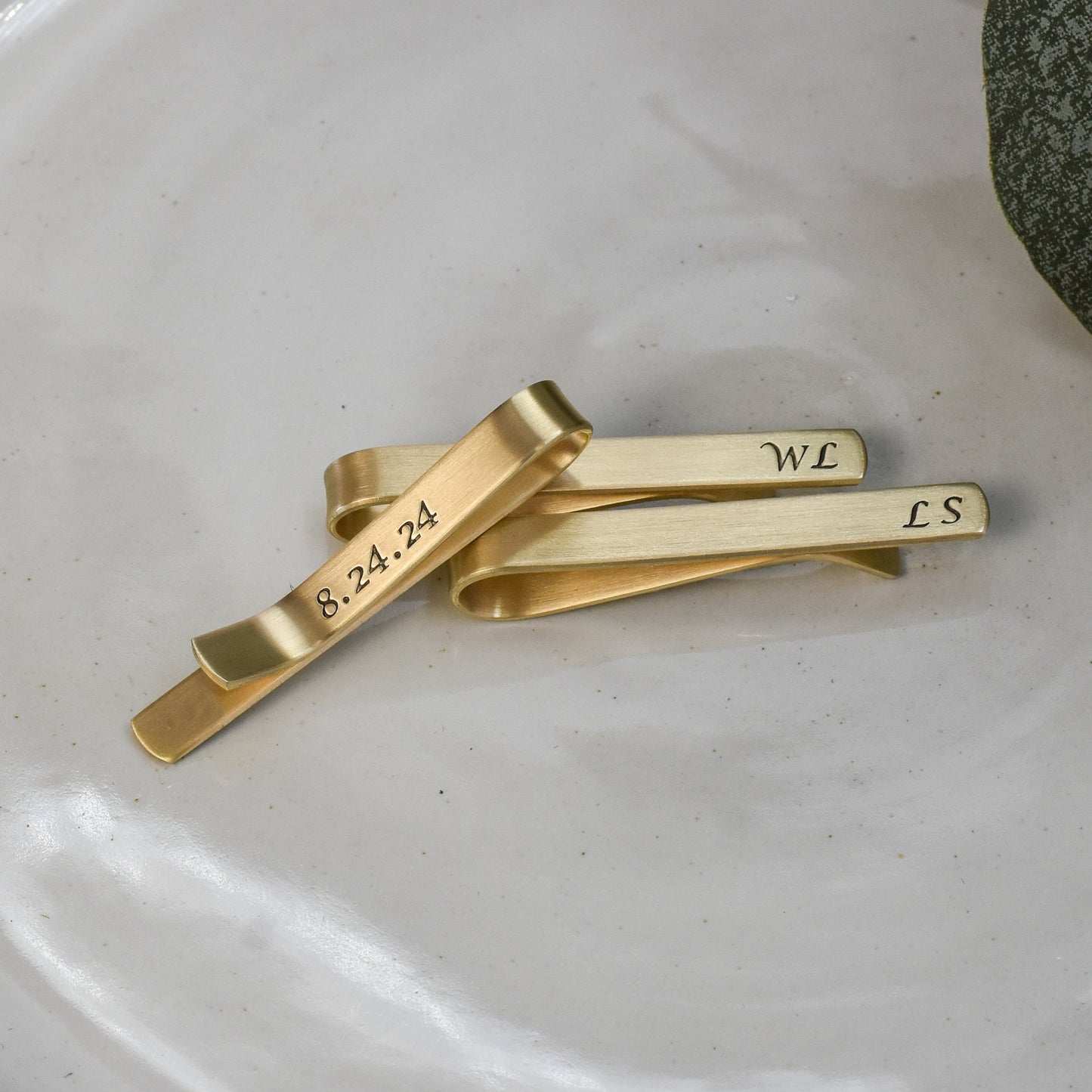 Personalized gold brass tie clip with hidden date on back in calligraphy font.