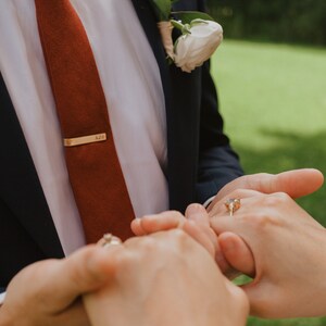 Review photo of groom holding bride's hands with personalized gold tie bar with groom's initials handmade by 321 Simple Creations.