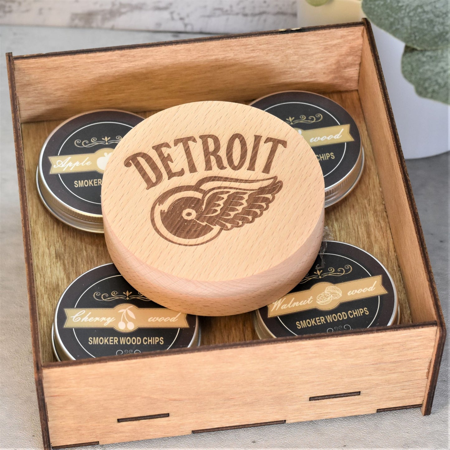 A wooden box with a lid, containing four small tins labeled 'SMOKER WOOD CHIPS' and one tin with a 'DETROIT' engraving on the lid, indicating it's a custom engraved sports themed cocktail smoker kit.